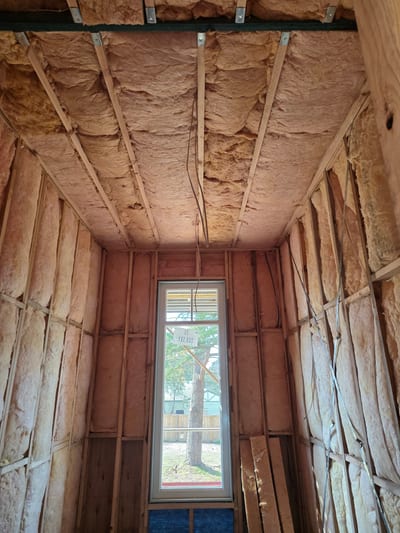 Pink insulation batts laid between ceiling joists in a roof space